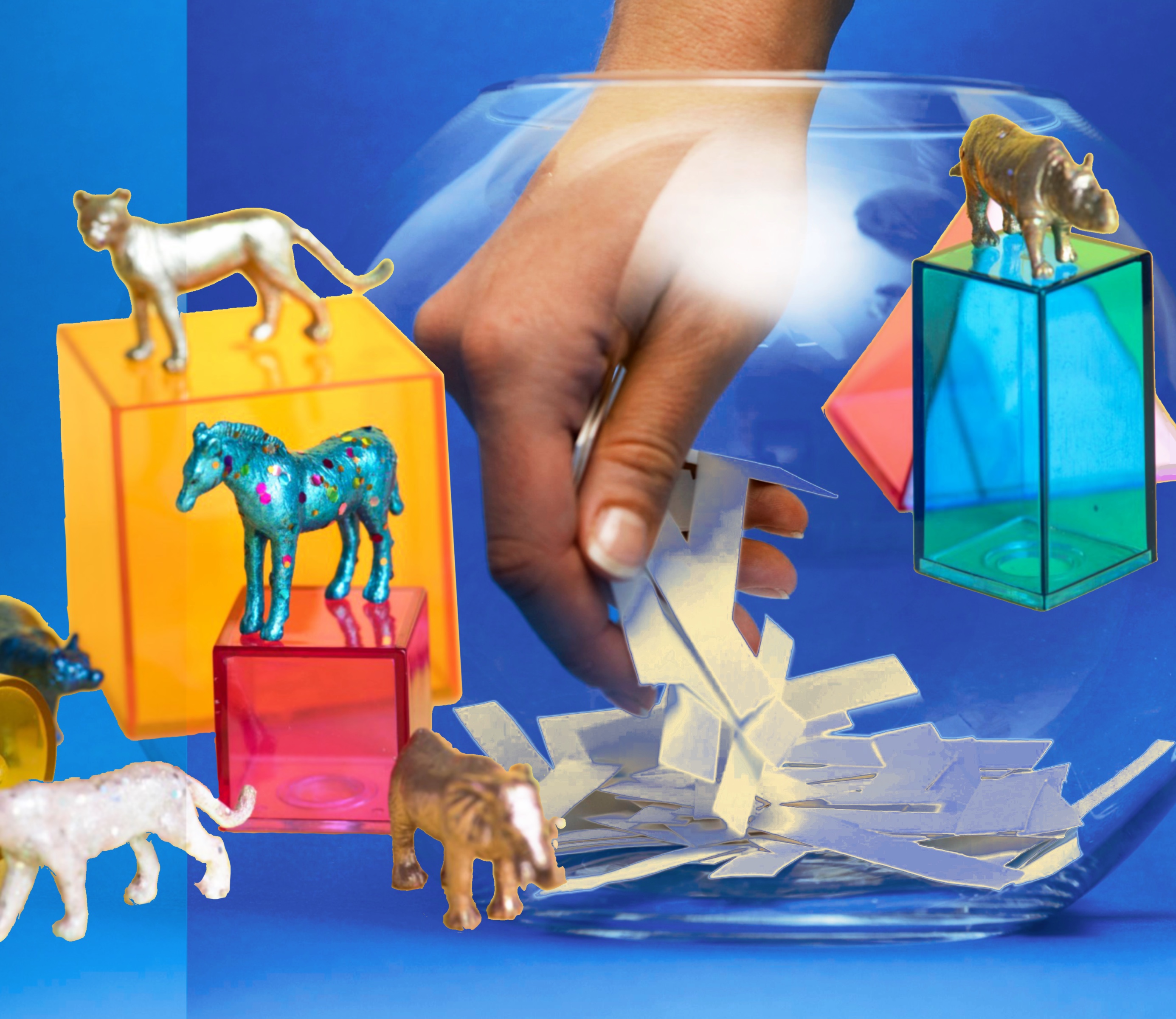 a hand reaching into a fish bowl and some toy horses on blocks