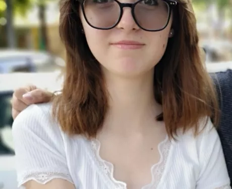 a young woman in glasses and a white shirt smiles at the camera