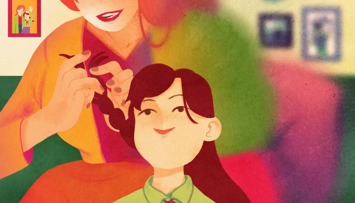 A young girl has her hair braided by her mother