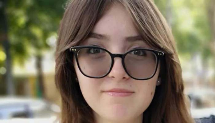 a young woman in glasses and a white shirt smiles at the camera