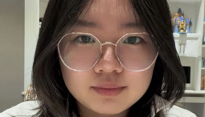 Image of a girl's face. She has dark hair and is wearing large round glasses.