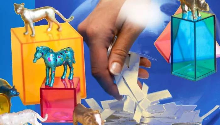 a hand reaching into a fish bowl and some toy horses on blocks